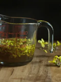 measuring cup filled with yellow flowers and golden syrup.