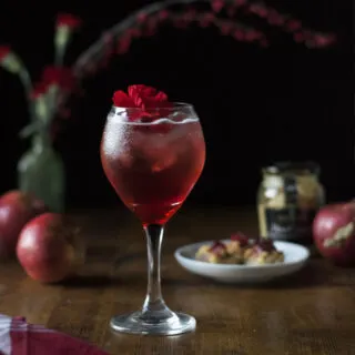 wine glass filled with a red bubbly cocktail with red flower.
