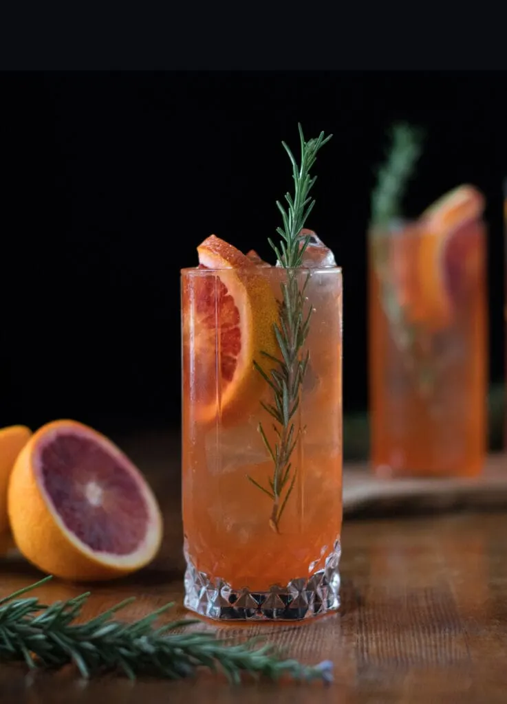 two highball glasses filled with an orange drink and blood orange slices.