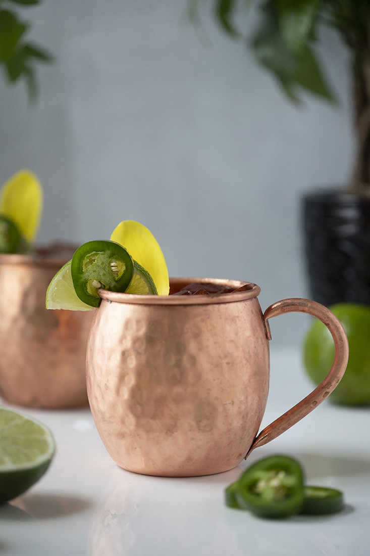 copper mule mugs garnished with jalapeno and flower petals