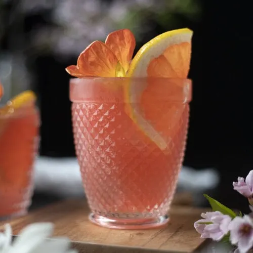 pink cocktail in a rocks glass with a slice of pink grapefruit