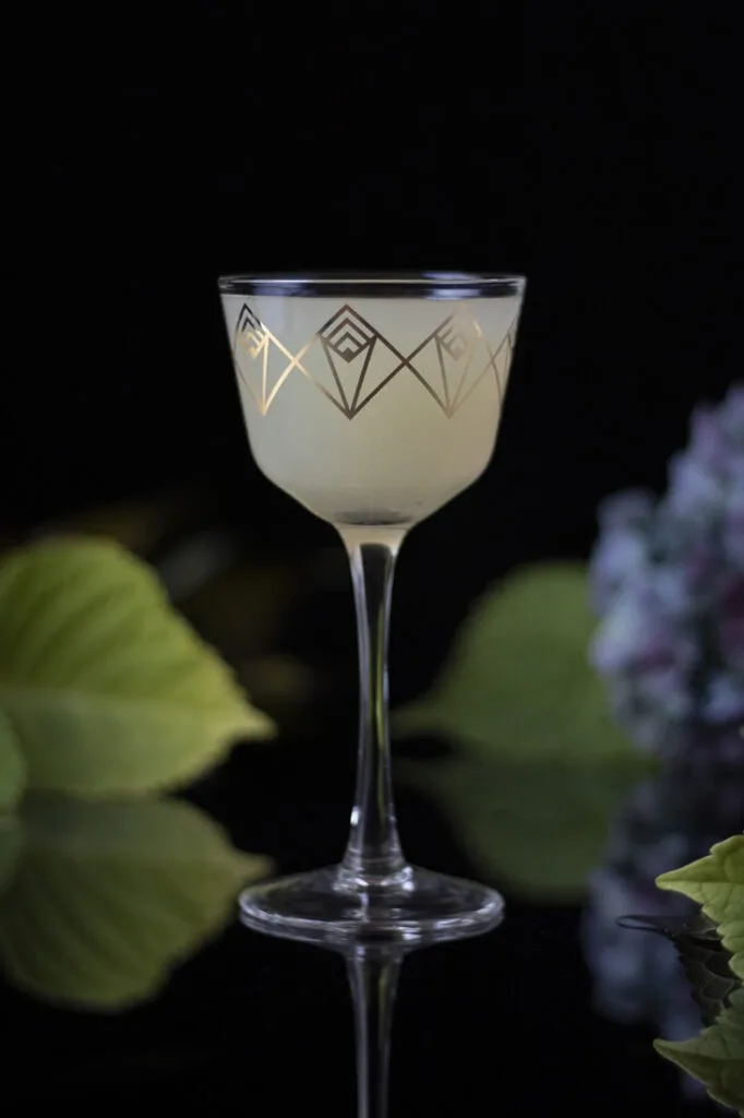 white cocktail in a gold embossed Nick and Nora glass