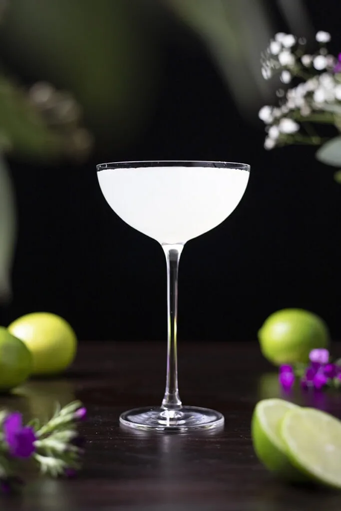 white cocktail on a table with limes