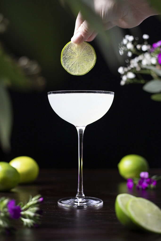 garnishing a cocktail with a lime wheel