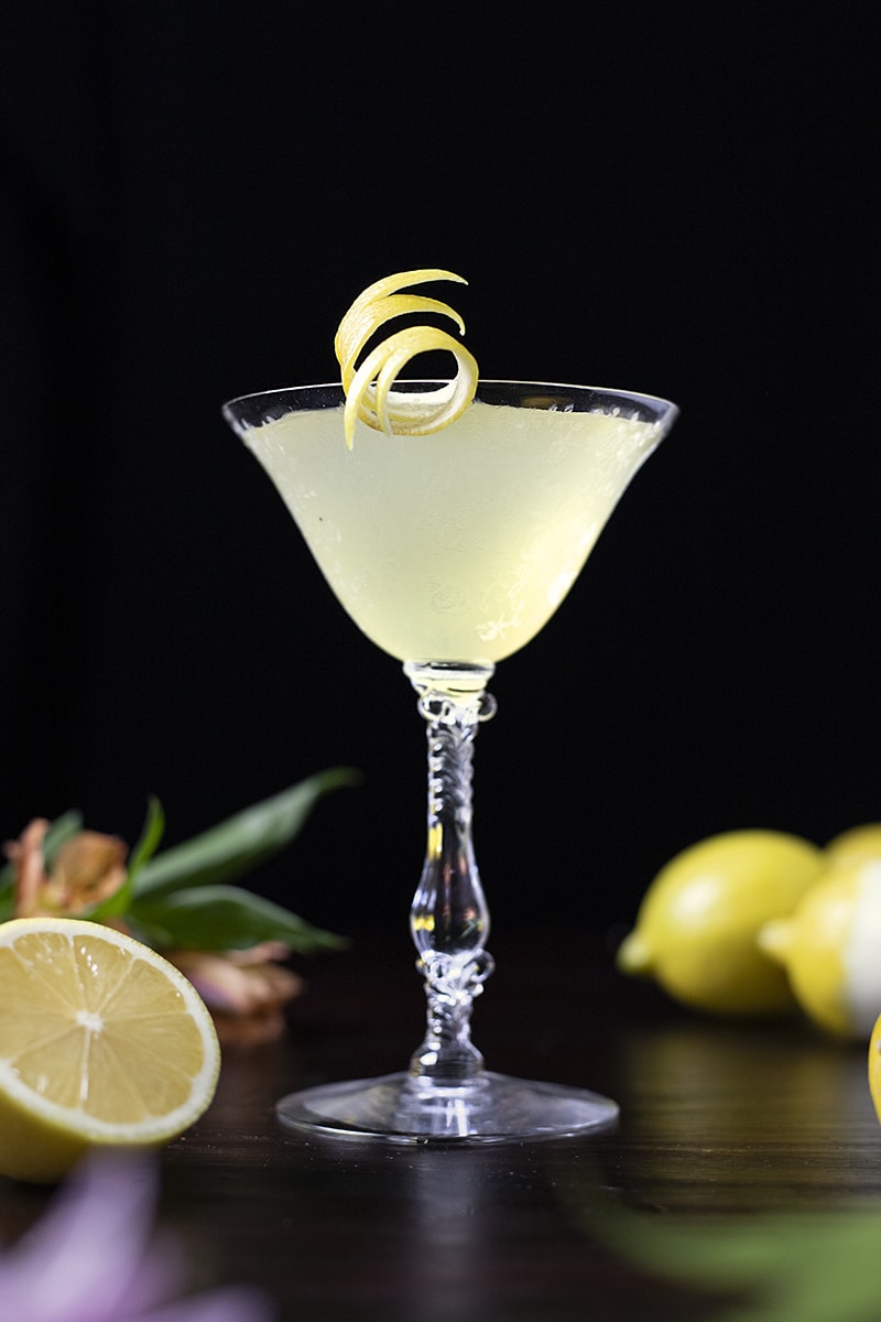 yellow cocktail in a vintage coupe glass wwith lemons