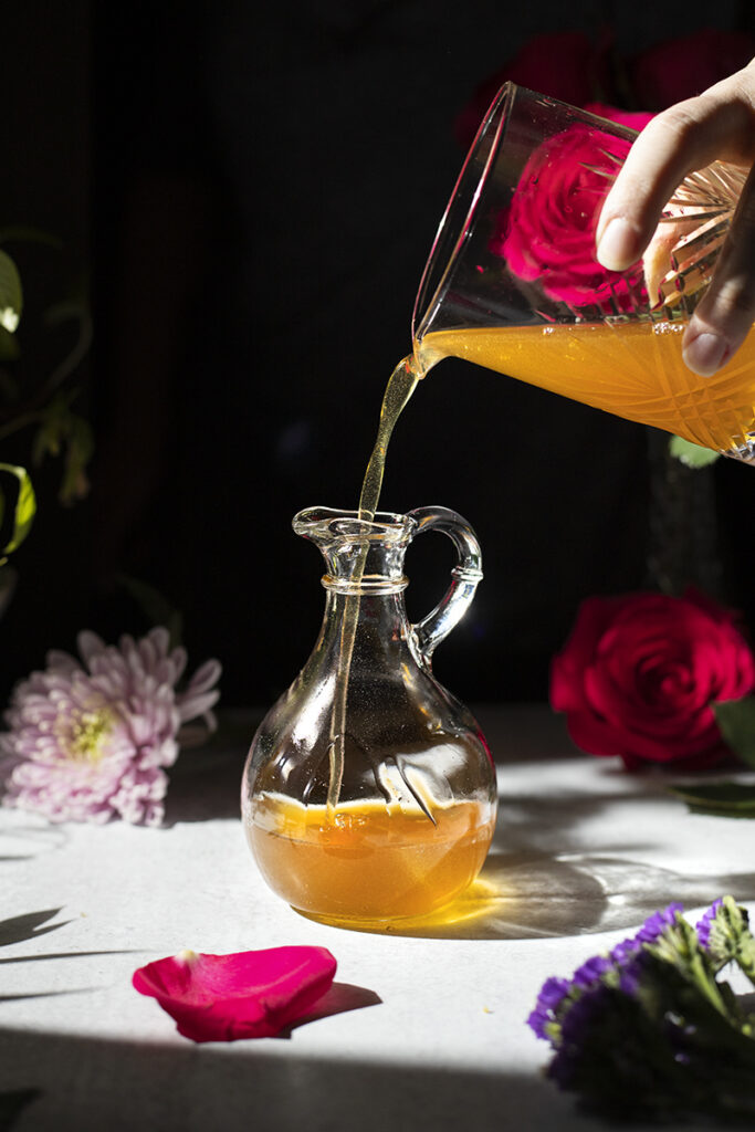 pouring honey syrup into a small pitcher