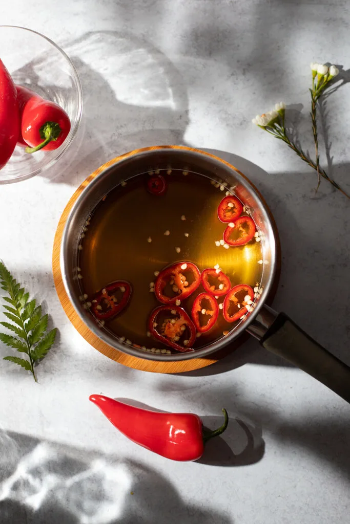 overhead view of a saucepan with honey and sliced red peppers in it