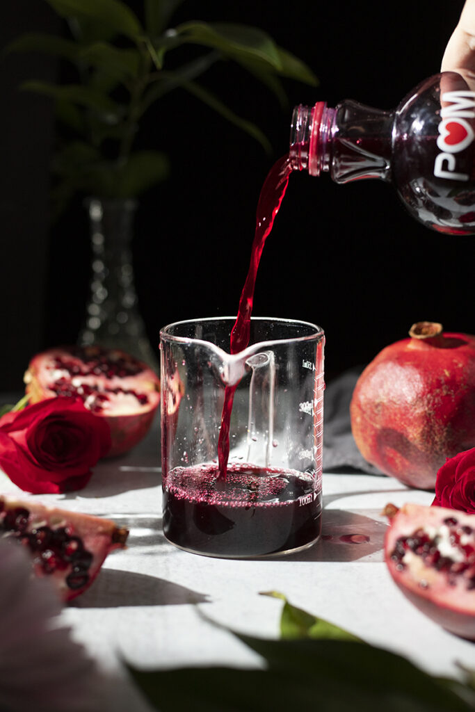 pouring pomegranate juice into a measuring cup