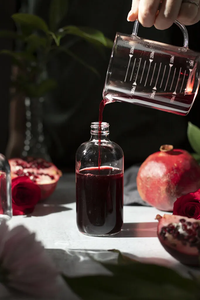 pouring grenadine syrup into an apothecary bottle