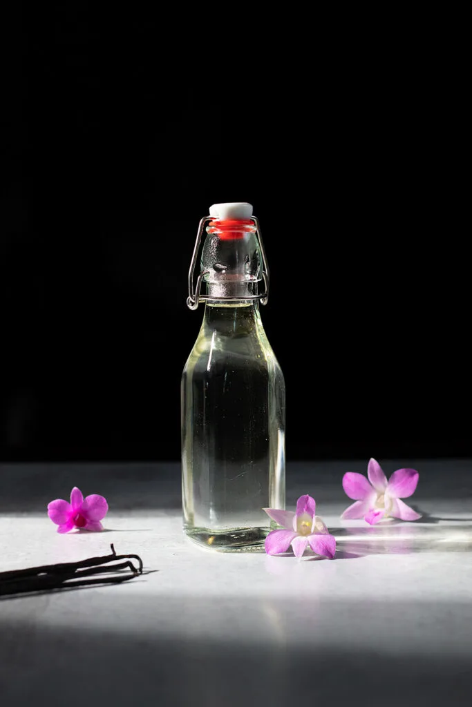 a swing top bottle of clear vanilla syrup with orchids.