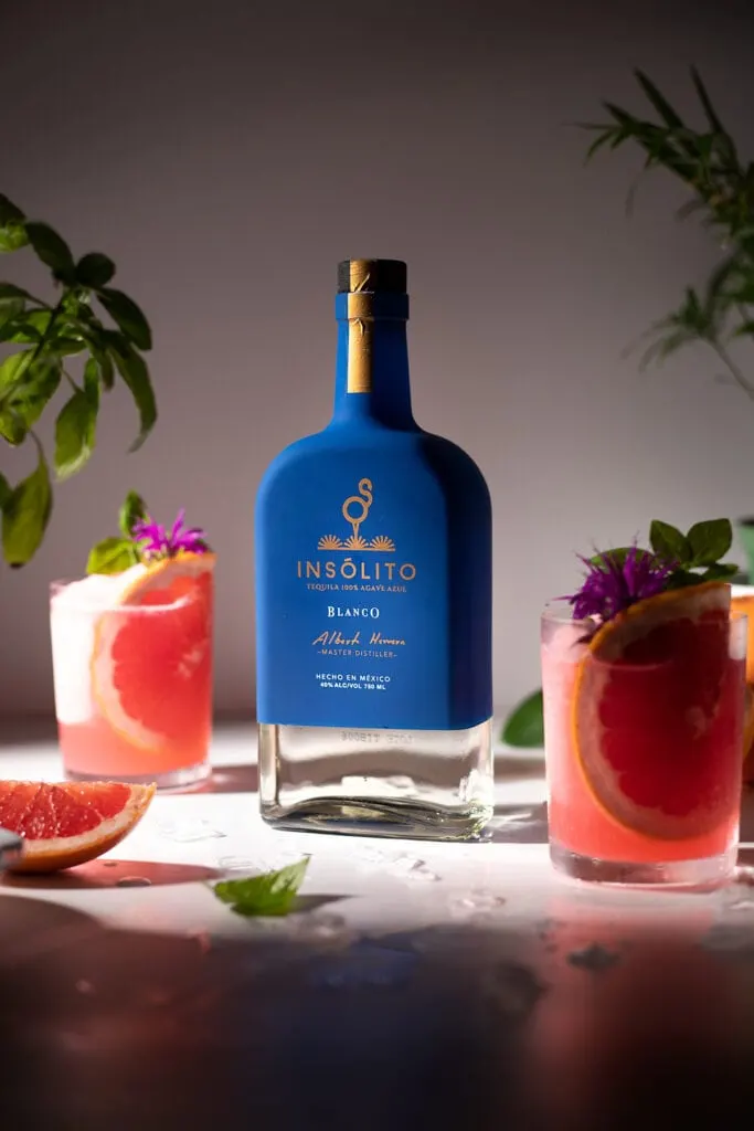 blue Insolito tequila bottle with glasses of frozen Palomas.