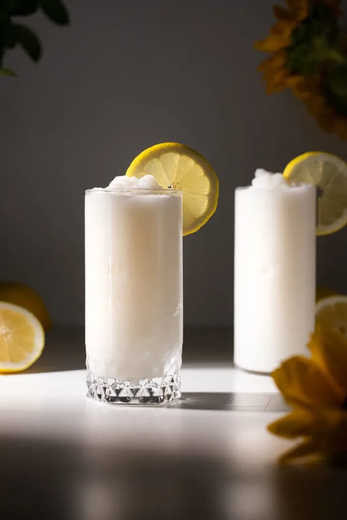 two glasses of frozen whipped lemonade with lemon wheels.