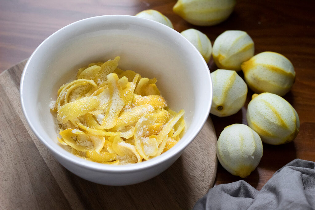 white mixing bowl filled with lemon peels and sugar.