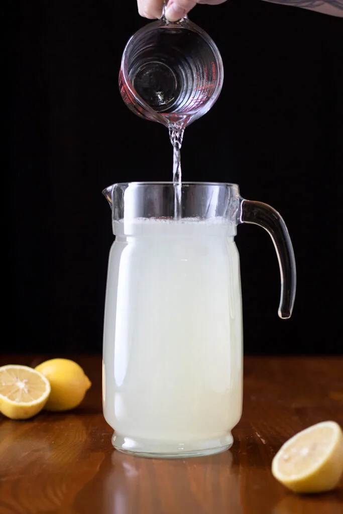 pouring water into pitcher to make lemonade.