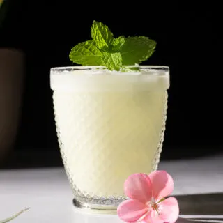 close up of white drink in lowball glass with mint.