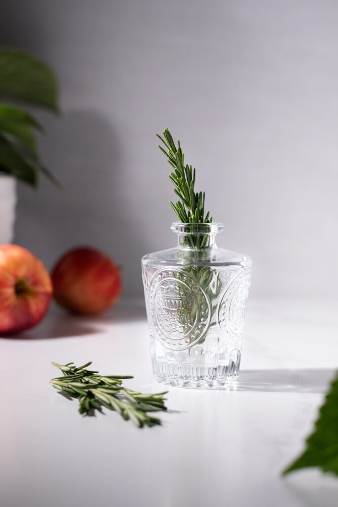 a small glass vase with a large sprig of fresh rosemary.