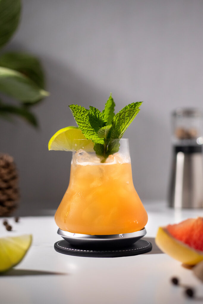 a pale orange cocktail garnished with lime and mint.
