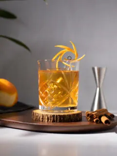 a fancy rocks glass filled with a golden brown cocktail.