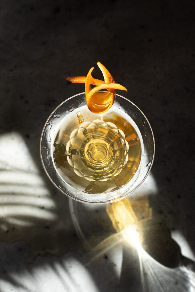 an overhead view of a pale yellow martini in a vintage etched glass.