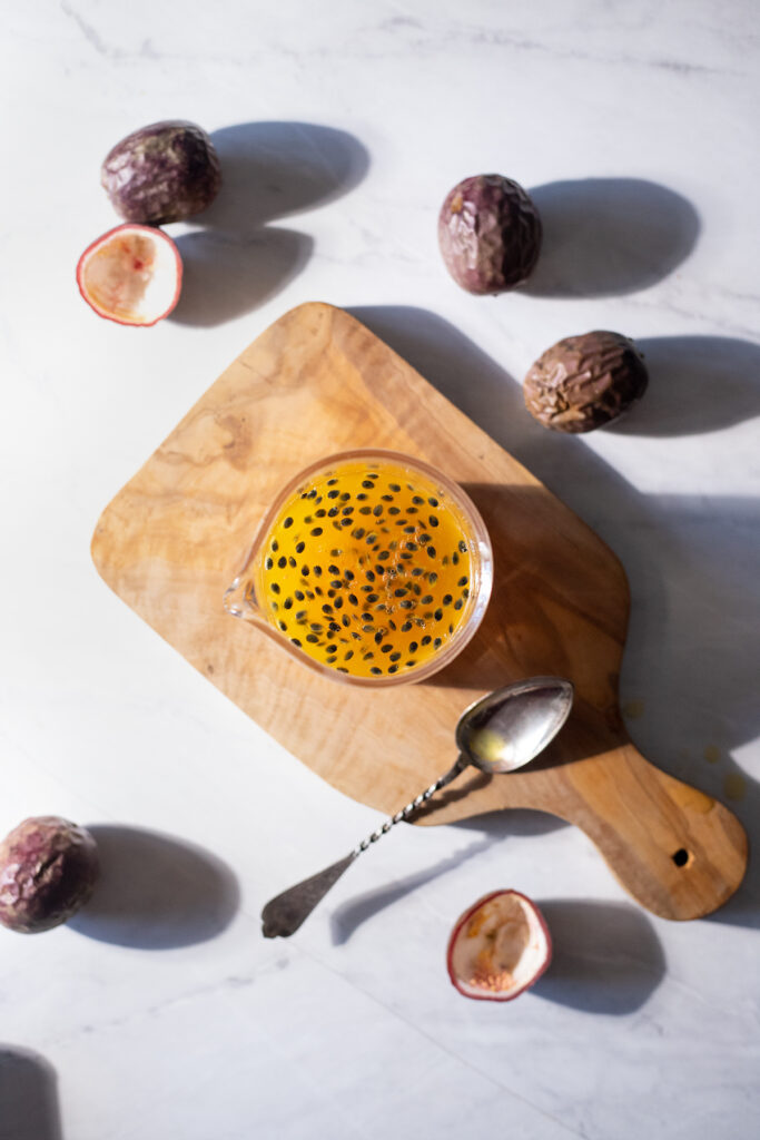 passion fruit pulp in a glass jar on a cutting board.