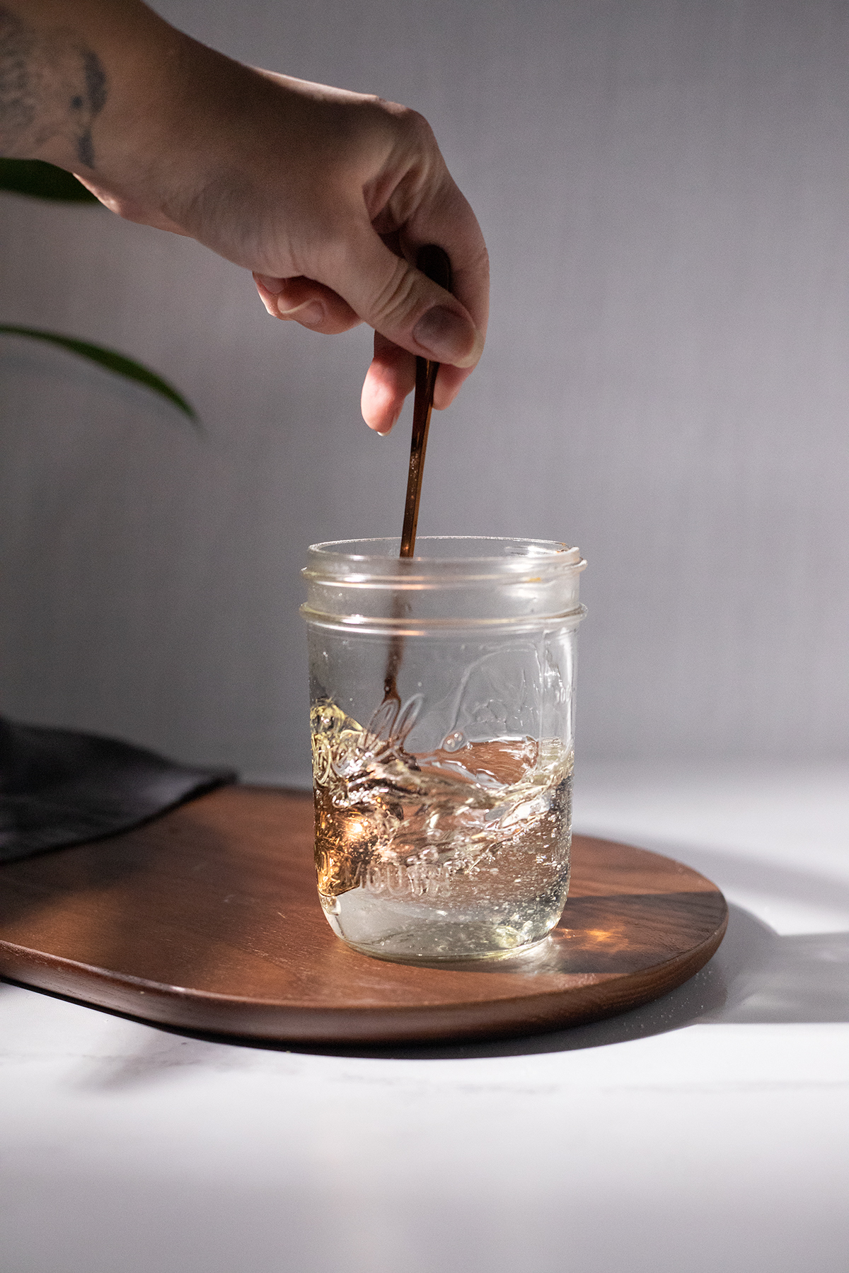 https://www.moodymixologist.com/wp-content/uploads/2022/10/stirring-simple-syrup-with-a-bronze-spoon-in-a-glass-jar.jpg