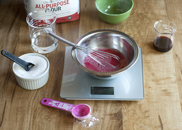 bright pink liquid in a metal mixing bowl with a metal whisk.