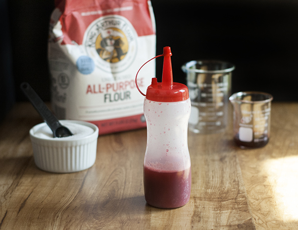 dark pink liquid in a plastic squeeze bottle next to ingredients.
