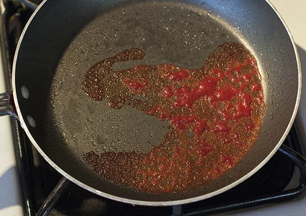 a failed red coral tuile cookie that is burnt on the edges.