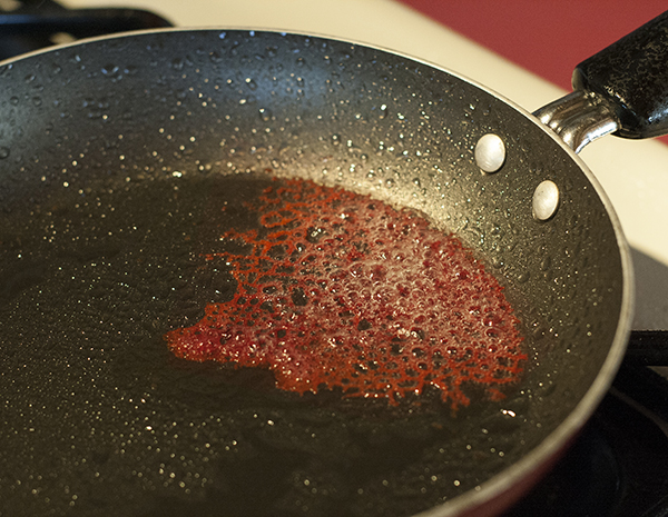 red coral tuile cookie in a pan with bubbling coconut oil.
